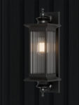 A timeless black outdoor wall lantern featuring ribbed glass panels and a classic silhouette, designed to provide warm, elegant illumination for exterior spaces.