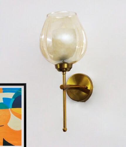 Modern wall sconce with amber glass shade and gold metal base, providing warm ambient lighting on a clean minimalist interior wall.