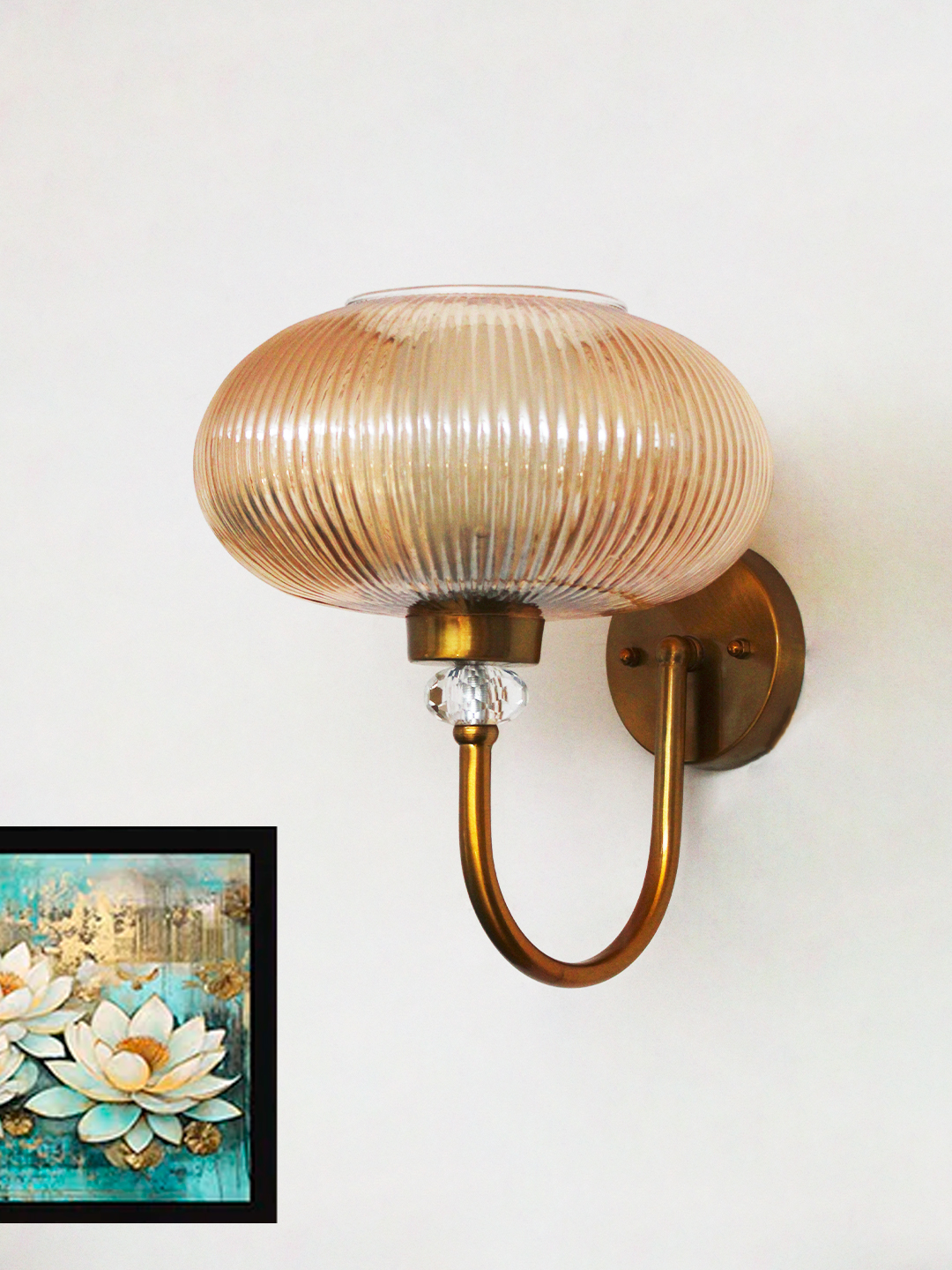 Brass Wall Sconce with Ribbed Amber Glass Shade Brass wall sconce with curved metal arm and amber ribbed glass shade mounted on a white wall, casting warm ambient light in a modern interior.