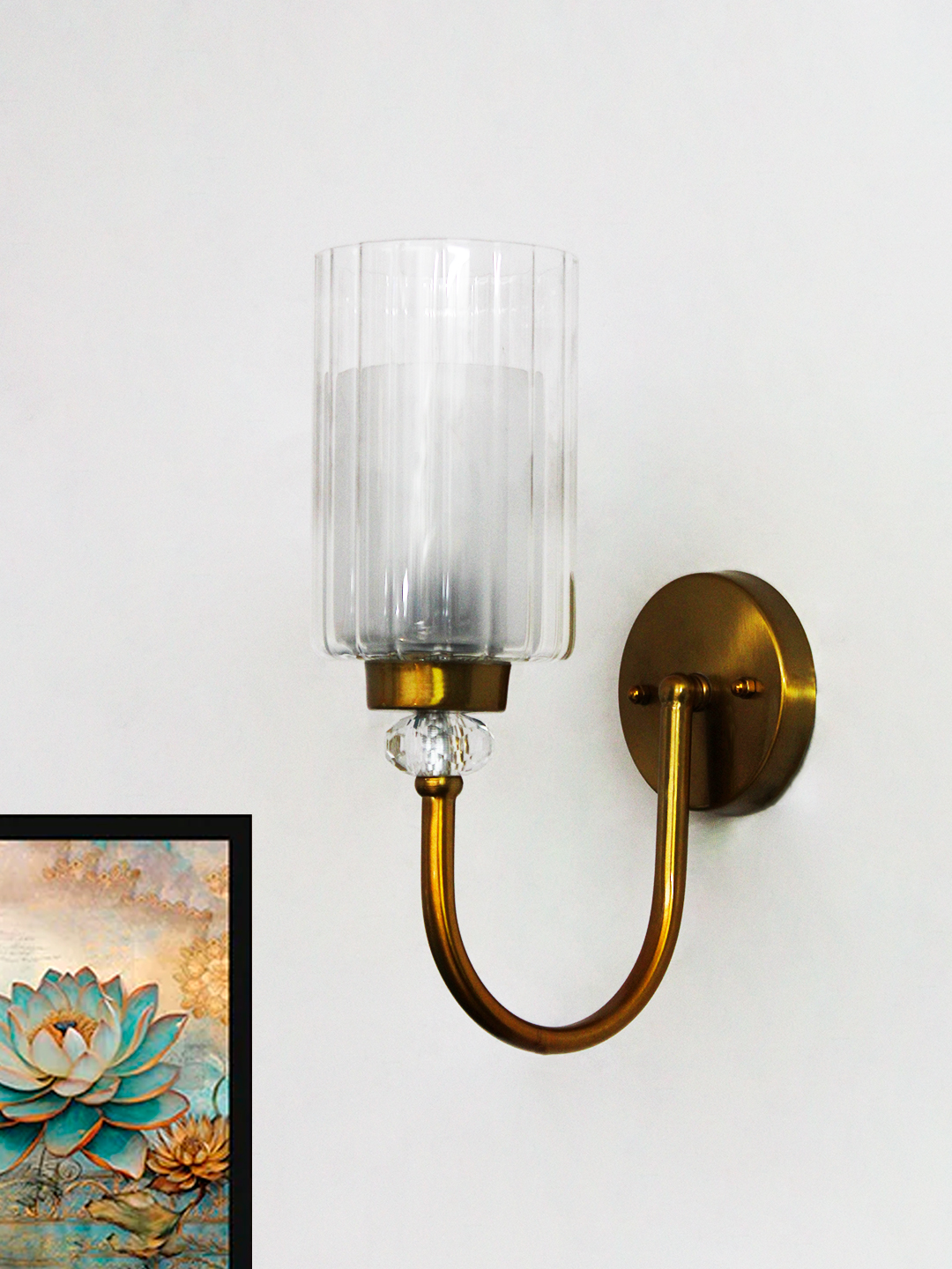 Brass Wall Sconce with Clear Ribbed Glass Shade Wall Sconce with clear ribbed glass cylinder shade and gold curved arm mounted on a white wall