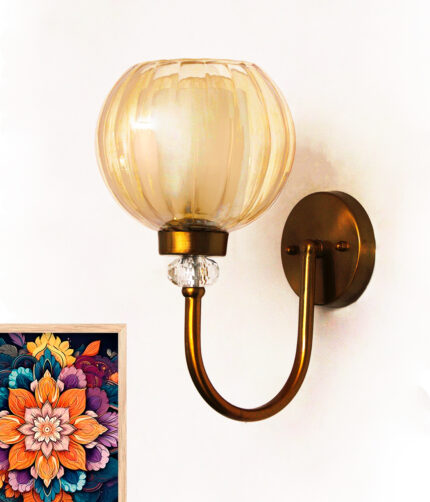 Amber Glass Globe wall sconce with ribbed glass shade and gold curved arm glowing warmly on a white wall
