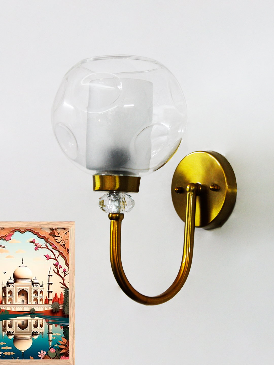 Contemporary Brass Sconce with Textured Glass Shade Gold wall sconce with curved arm and textured glass shade mounted on a white wall, providing warm ambient lighting.