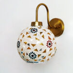 Handcrafted brass wall light with colorful mosaic glass shade casting warm ambient glow on wall decor