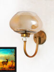 Designer Globe wall light with amber glass shade and brass finish mounted on a wall, featuring a curved arm and warm ambient lighting