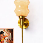 Lamp Amber Glass wall light with sculpted amber shade and brass finish, featuring a vertical stem design and warm ambient illumination