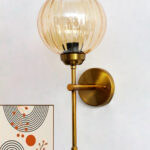 Elegant brass wall light with ribbed amber glass shade, modern wall sconce mounted on a white wall providing warm ambient lighting for stylish interiors
