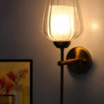 Ribbed Glass Lamp wall light with clear textured glass shade and brushed gold metal base mounted on a white wall, providing elegant ambient lighting for modern interiors.