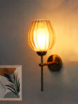 Amber Glass Lamp wall light with textured amber glass shade and brass finish, mounted on a white wall, giving a warm and cozy glow.