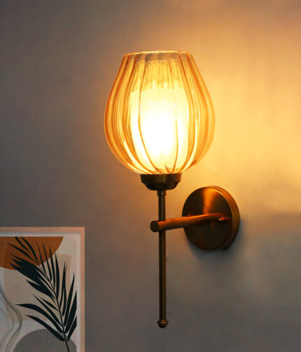 Amber Glass Lamp wall light with textured amber glass shade and brass finish, mounted on a white wall, giving a warm and cozy glow.