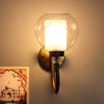 Gold wall sconce with curved arm and textured glass shade mounted on a white wall, providing warm ambient lighting.