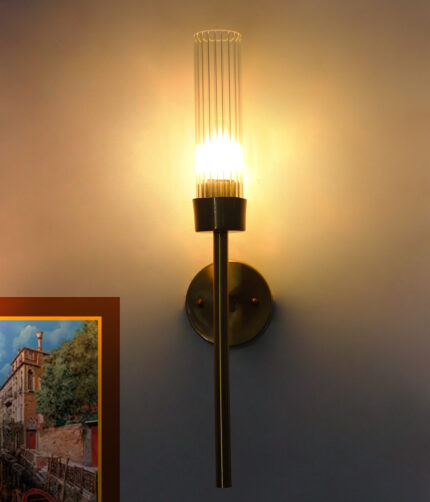 Slim Tube Wall Lamp with brass finish and vertical cylindrical glass shade mounted on a wall, featuring a minimalist modern design and warm ambient lighting.