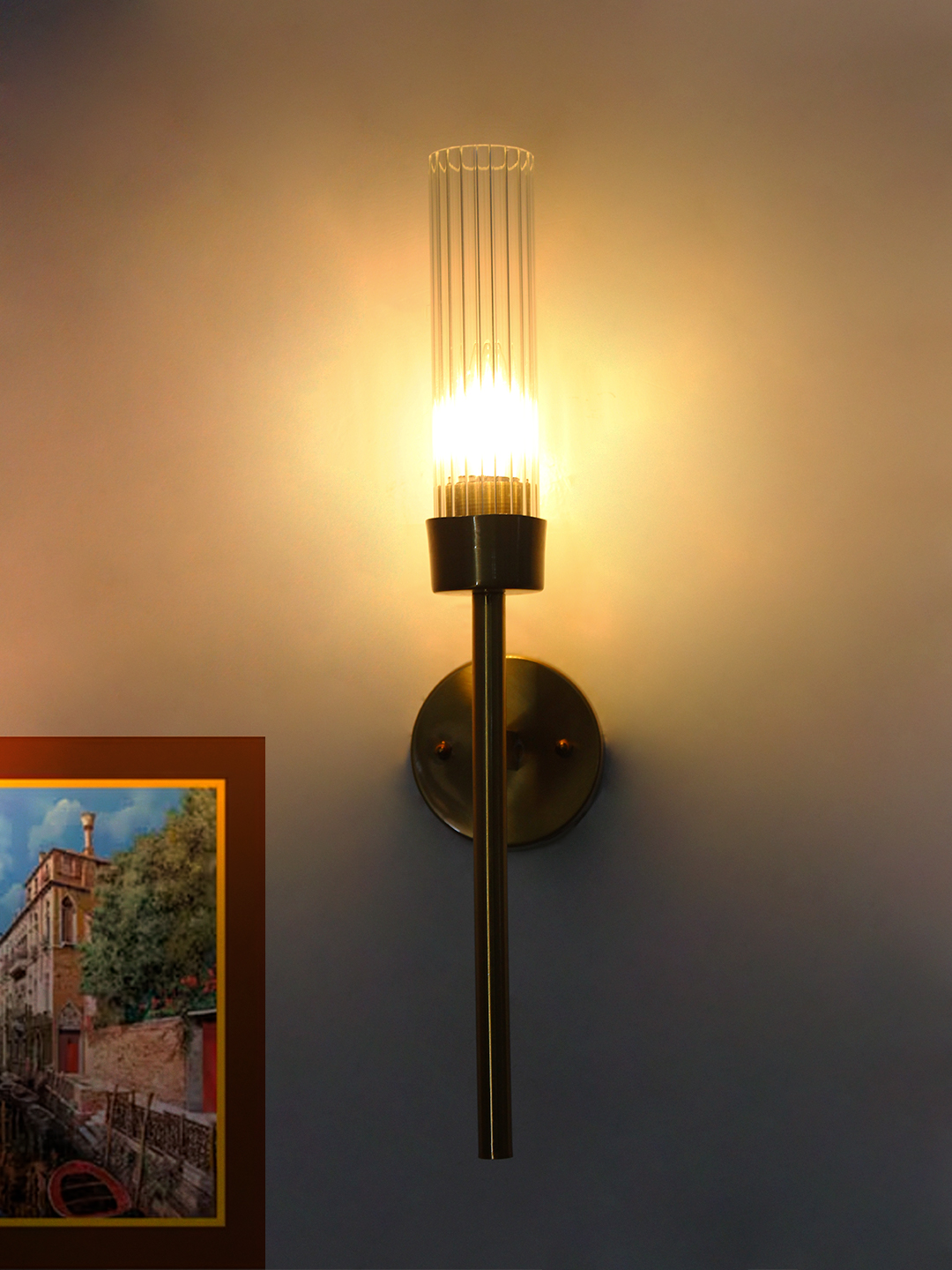 Clear Glass Slim Tube Wall Lamp Brass Slim Tube Wall Lamp with brass finish and vertical cylindrical glass shade mounted on a wall, featuring a minimalist modern design and warm ambient lighting.