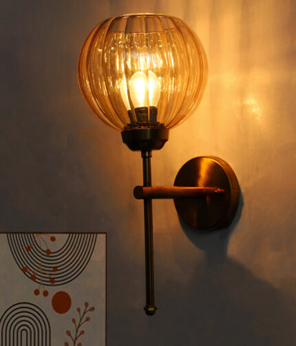 Elegant brass wall light with ribbed amber glass shade, modern wall sconce mounted on a white wall providing warm ambient lighting for stylish interiors