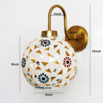 Handcrafted brass wall light with colorful mosaic glass shade casting warm ambient glow on wall decor