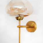 Amber Kachori Glass wall light with smooth curved amber glass shade and brushed brass mount on white background