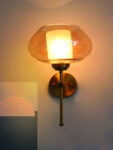 Amber Kachori Glass wall light with smooth curved amber glass shade and brushed brass mount on white background