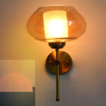 Amber Kachori Glass wall light with smooth curved amber glass shade and brushed brass mount on white background