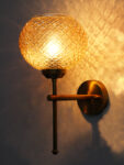 Amber Crystal Globe Glass wall light with textured diamond-pattern glass shade and brushed brass mount on white background