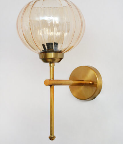 Amber Kharbhuja Glass wall light with ribbed amber glass shade and brushed brass mount on white background