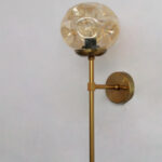 Amber Glass Globe Modern Light wall fixture with textured amber glass globe and brass arm mounted on white wall