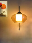 Down Kachori Glass wall light with downward amber glass shade and curved brass arm, glowing warmly on wall