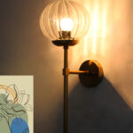 Clear Kharbuja Glass wall light with ribbed transparent glass globe and brass mount on white wall