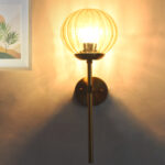 Amber Kharbuja Glass wall light with ribbed amber glass globe and brass mount, glowing warmly on wall
