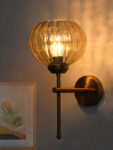 Amber Kharbhuja Glass wall light with ribbed amber glass shade and brushed brass mount on white background