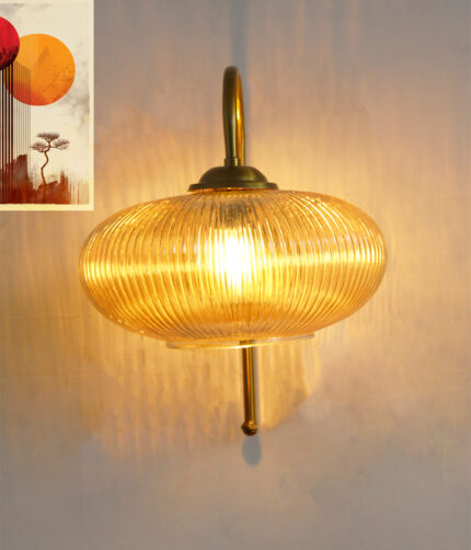 Down Ribbed Amber Glass wall light with ribbed amber shade and curved brass arm, casting warm ambient glow on wall