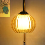 Amber Kharbhuja Glass wall light with ribbed amber glass shade and curved brass arm mounted on wall