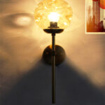 Amber Glass Globe Modern Light wall fixture with textured amber glass globe and brass arm mounted on white wall
