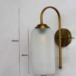 White Milky Froasted Glass wall light with cylindrical frosted glass shade and curved brass arm mounted on wall