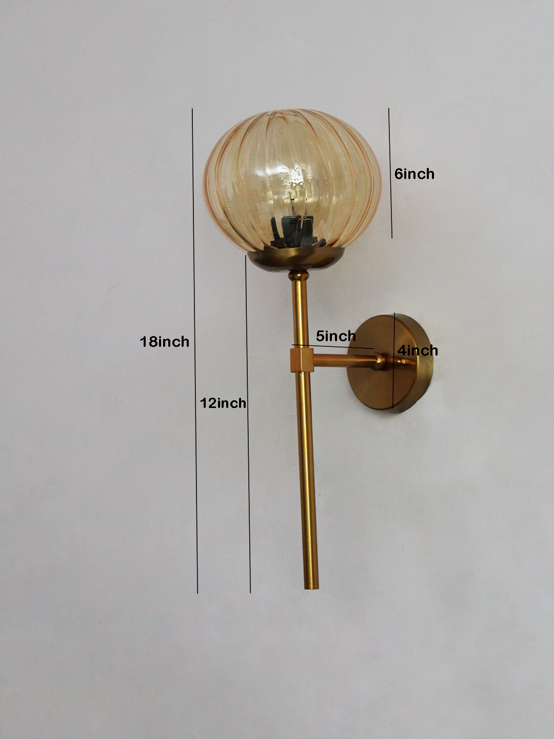 Contemporary Brass Funner Wall Lamp with Amber Kharbuja Glass Amber Kharbuja Glass wall light with ribbed amber glass globe and brass mount, glowing warmly on wall