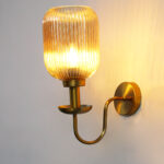 Amber Glass Curved Arm Wall Lamp with ribbed glass shade and antique brass finish for bedroom, living room, and hallway décor