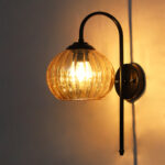 Hanging Black Wall Lamp with amber ribbed glass shade and matte black curved metal wall mount for elegant modern indoor lighting