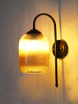 Amber Ribbed Glass wall lamp with amber ribbed cylindrical glass shade and matte black curved metal wall mount for elegant modern indoor lighting