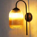 Amber Ribbed Glass wall lamp with amber ribbed cylindrical glass shade and matte black curved metal wall mount for elegant modern indoor lighting