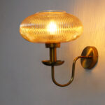 Kachori Amber Glass Wall Lamp with ribbed amber glass shade and antique brass curved arm for bedroom, living room, and hallway décor