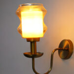 Damru Glass Wall Sconce with amber designer glass shade and brass finish curved arm decorative wall lamp for bedroom and living room