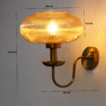 Kachori Amber Glass Wall Lamp with ribbed amber glass shade and antique brass curved arm for bedroom, living room, and hallway décor