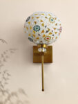 White Tipni Colourful Glass wall light with mosaic dome shade, floral and geometric patterns, and brass finish arm for decorative ambient lighting