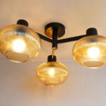 Solara 3-Light chandelier with three ribbed amber glass shades and a matte black metal frame, modern semi-flush ceiling light for dining rooms, living rooms, kitchens, and bedrooms.