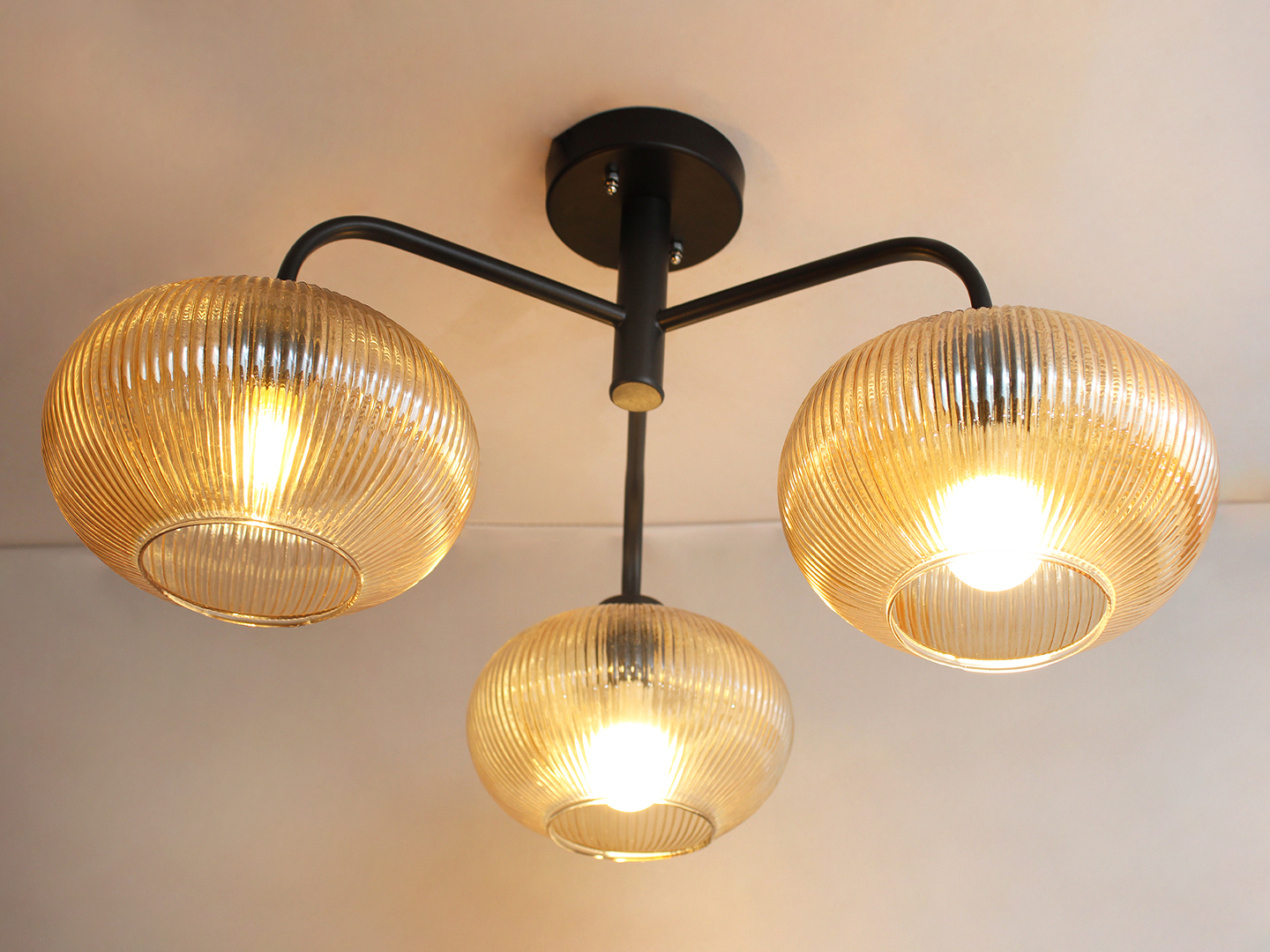 Modern 3-Light Ribbed Glass Chandelier Ribbed Glass Chandelier with three amber ribbed glass shades and a matte black metal frame, modern semi-flush ceiling light for dining room, living room, and kitchen.