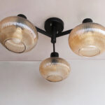 Solara 3-Light chandelier with three ribbed amber glass shades and a matte black metal frame, modern semi-flush ceiling light for dining rooms, living rooms, kitchens, and bedrooms.