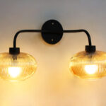 **Alt Text:** **2-Light Ribbed Glass** wall light with dual amber ribbed glass shades and a matte black metal frame, modern wall-mounted fixture for bedrooms, hallways, living rooms, and dining spaces.