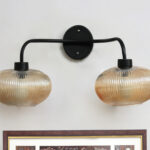 **Alt Text:** **2-Light Ribbed Glass** wall light with dual amber ribbed glass shades and a matte black metal frame, modern wall-mounted fixture for bedrooms, hallways, living rooms, and dining spaces.