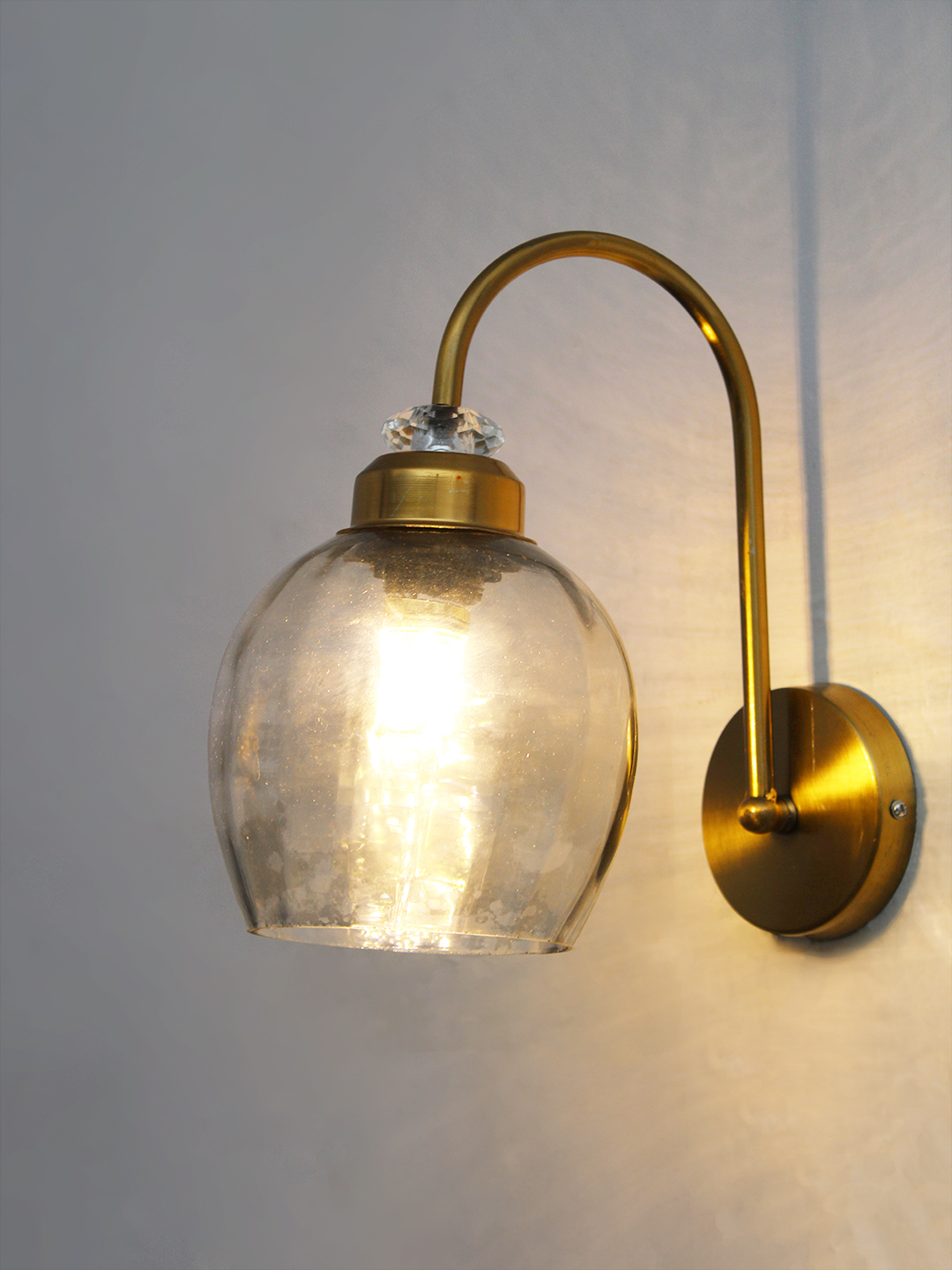 Antique Brass Smoked Glass Wall Sconce Antique brass smoked glass wall light with curved arm and round wall mount