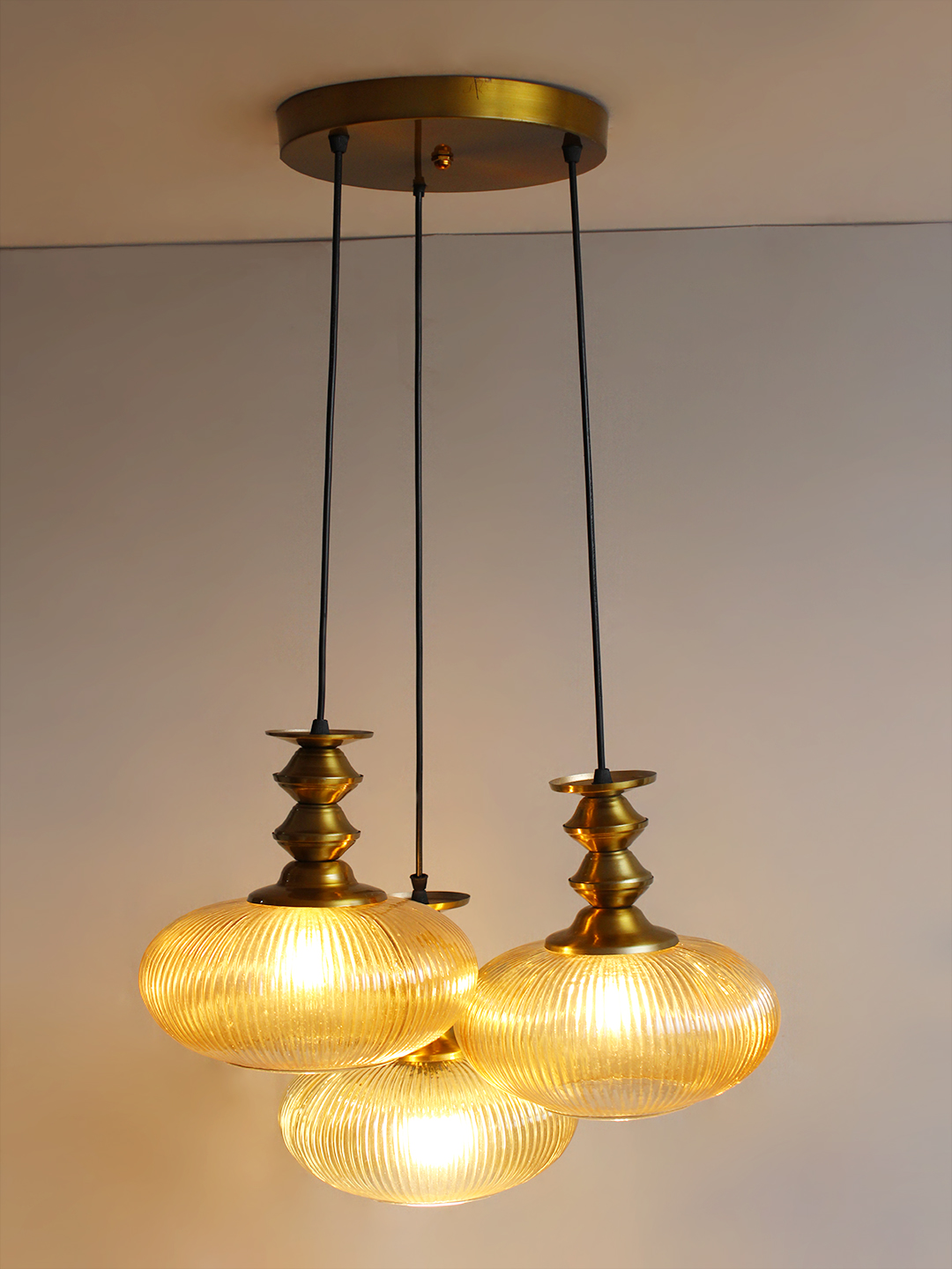 Ribbed Amber Kachori Glass Cluster Hanging Light Ribbed Amber Kachori Glass 3-light adjustable pendant ceiling light with three rounded textured amber ribbed glass shades, elegant golden metal holders, 9-inch ceiling canopy, and 23-inch adjustable hanging cords.