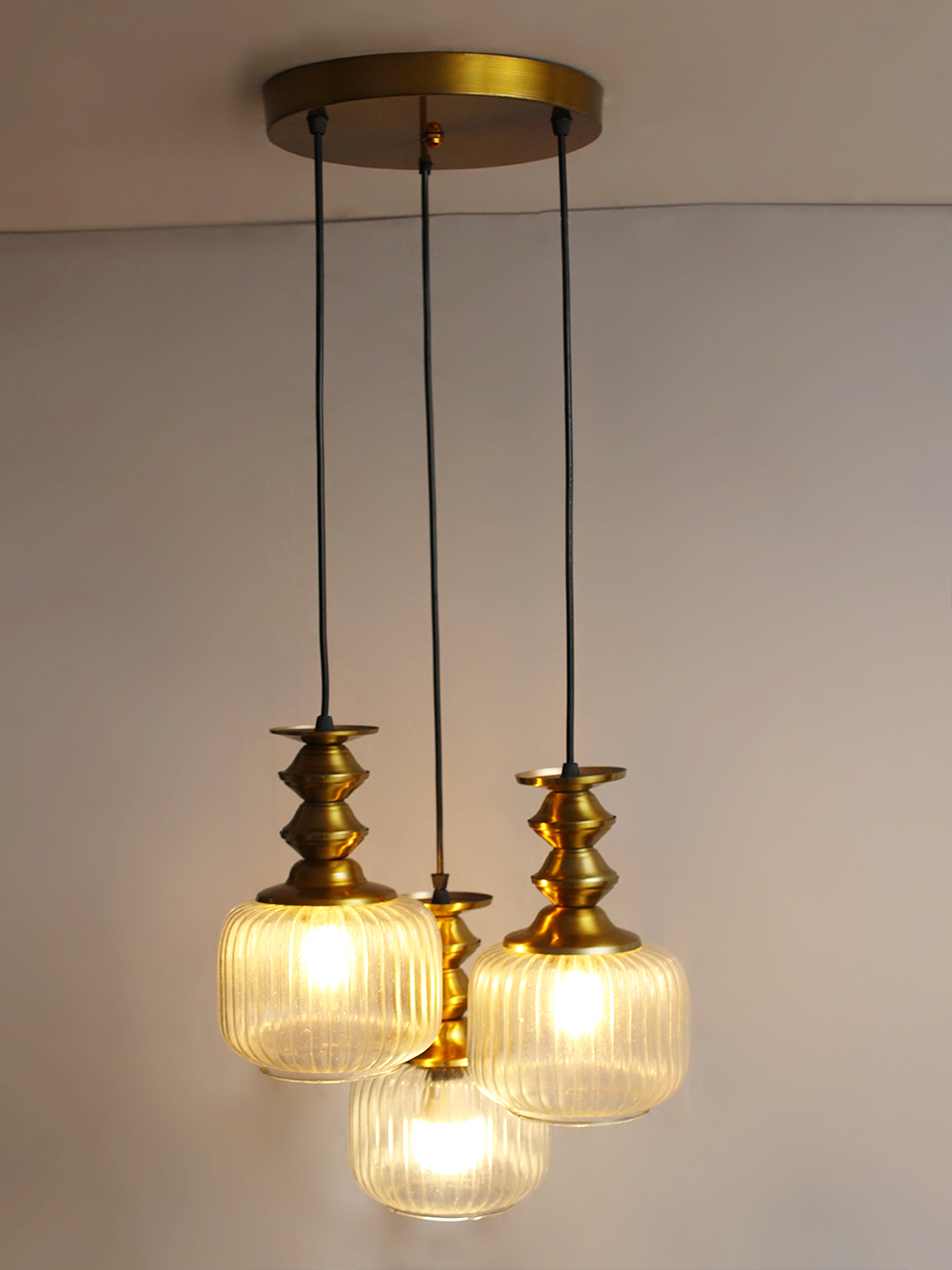3-Light Ribbed Clear Glass Cluster Hanging Light 3-Light Ribbed Clear Glass adjustable pendant ceiling light with three 6-inch textured clear ribbed glass shades, decorative golden metal holders, black adjustable hanging cords, 9-inch circular canopy, and up to 23-inch adjustable height.