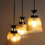 3-Light Ribbed Glass cluster hanging light with three clear ribbed shades, adjustable 23-inch height and black ceiling canopy.